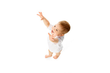 Little cute baby boy, child in t-shirt raising hands upwards isolated over white studio background. Attentive kid. Concept of childhood and family, care, parenthood, infancy and heath