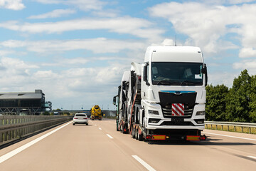 Back view of semi-trailer flatbed vehicle deliverying many new electric trucks sale automotive...