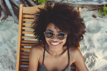 Cheerful young afro girl wears sunglasses and looks at the camera, while enjoying her vacation.