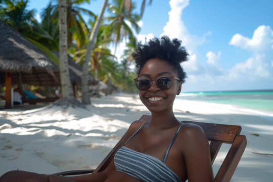 Cheerful young afro girl wears sunglasses and looks at the camera, while enjoying her vacation.