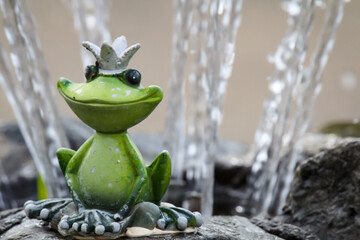 Eine Figur des Froschkönigs sitzt auf dem Rand eines Brunnens.
