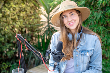 Portrait happy smiling young woman with headphones recording podcast outdoors in spring at sunset. High quality photo