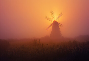 Obraz premium Windmill in the mist. A windmill rises from a misty field