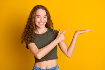 Fototapety  Photo of adorable cute girl wear stylish clothes arms demonstrate empty space logo brand isolated on yellow color background