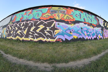 Fisheye shot of street art graffiti drawing on wall. Spray art artwork with different colors and outlines. Illegal vandalism concept
