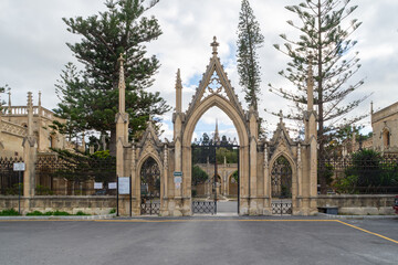 Paola, Malta - January 28th 2022: The entrance with a gatehouse on either side at the Santa Maria Addolorata Cemetery also known as the Addolorata Cemetery.  - obrazy, fototapety, plakaty
