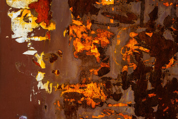 Close up of a brown rusted sheet metal surface with leftovers of peeled off paper advertisements.