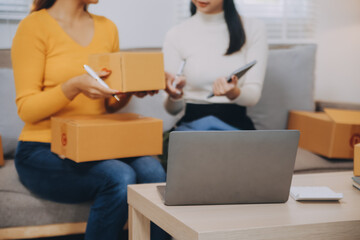 Asian SME business women use laptop computer checking customer order online shipping boxes at home....