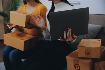 Asian SME business women use laptop computer checking customer order online shipping boxes at home....