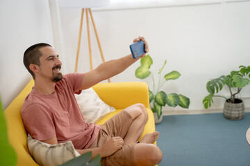 happy man taking selfie on mobile phone while sitting on couch. High quality photo