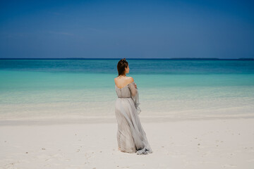 Fototapeta na wymiar woman walking on the beach in a beautiful dress