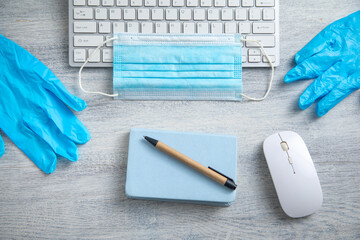 Medical mask, gloves and computer keyboard on the table.