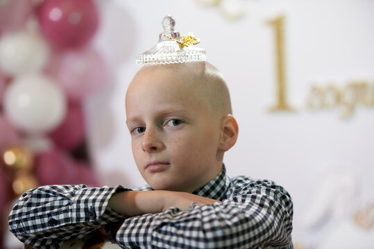 Bald boy 12 years old with a transparent crown on his head, at a party