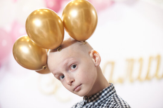 Bald boy 12 years old with a crown of balloons on his head, at a party