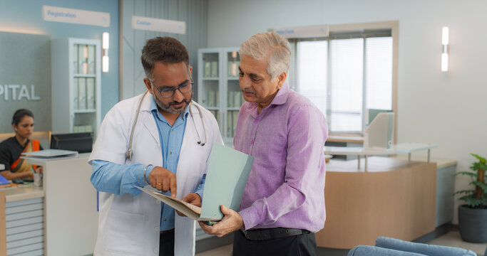 Indian Healthcare Service: Professional Medical Doctor Talking to His Patient, Sharing Good News about Health Treatment. Family Practitioner Giving Advice to a Senior Man and His Granddaughter