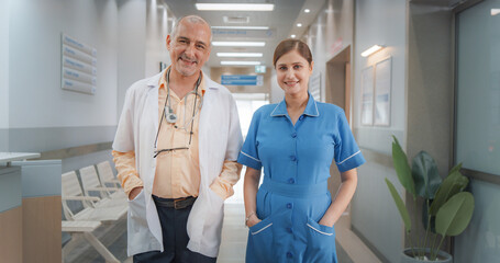 Obraz premium Two Friendly Indian Doctors: Team Portrait of Male Successful Medical Healthcare Professionals Standing in a Modern Hospital Office, Posing, Looking at Camera and Smiling. Doctor and Nurse on Duty