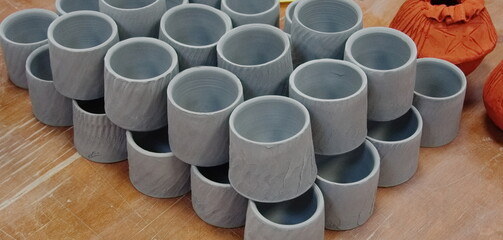 Collection Of Handmade Clay Pottery Cups Lined Up On Workbench