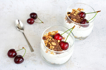 a glass with yogurt, muesli, chocolate and cherries top view