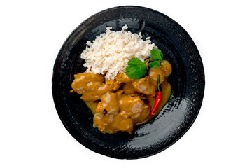 Juicy pieces of chicken with curry sauce and white rice on a plate on a white background, top view