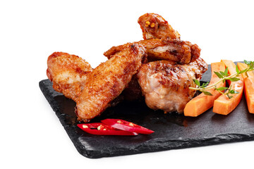 Grilled chicken pieces on a slate board with fresh vegetables isolated on white