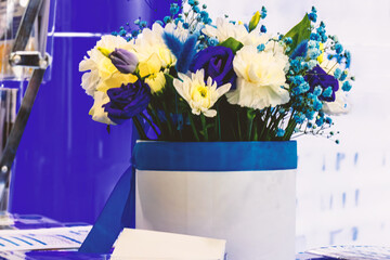 Table with a vase of flowers with a blue ribbon. The stage is set for a corporate business event.