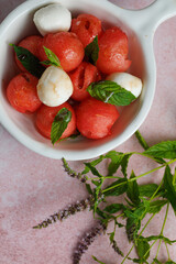 Watermelon Salad with mozzarella balls and mint on light rose background. healthy eating. Summer recipe concept