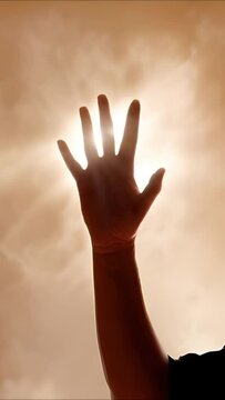 A hand is faithful and praising God in the air with sunlight and clouds for a spiritual religious concept