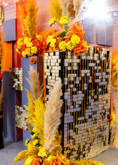 Part of the wall, decorated with a mosaic consisting of multi-colored tiles and gold details. The wall is decorated with yellow flowers, creating a visually appealing and vibrant display.
