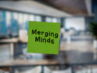 Post note on glass with 'Merging Minds'.