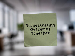 Post note on glass with 'Orchestrating Outcomes Together'.