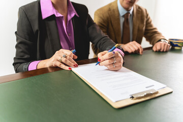 Two business professionals - engaged in signing a contract, focus on hands and document - legal...