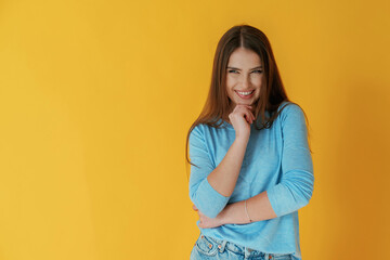 Having bad evil thoughts, smiling of joy. Young woman is against yellow background