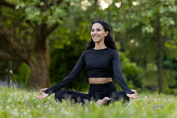 Young woman immersed in meditation, performing yoga in a peaceful green park, embodying health and...