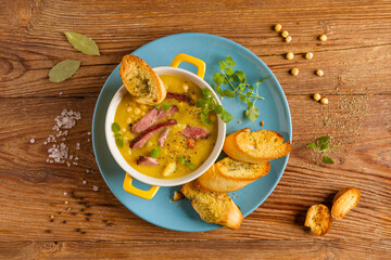 Traditional Polish pea soup. Prepared with smoked meat. Served in a yellow bowl with croutons. Home made.