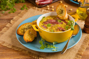Traditional Polish pea soup. Prepared with smoked meat. Served in a yellow bowl with croutons. Home made.