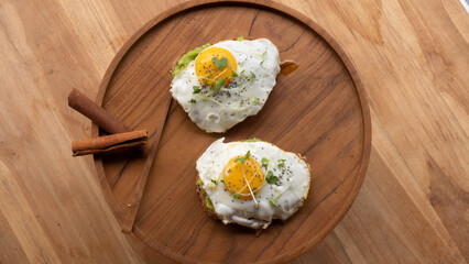 Sunnyside up egg on top of freshly smashed avocado sauce. Breakfast table with high nutritions vegan and vegetable food
