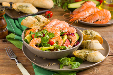 Spring salad with shrimp, mango and avocado. Served in a bowl, with croutons, sprinkled with roasted sunflower seeds.