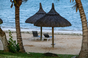Sun umbrella and beach beds on tropical coastline, in Mauritius