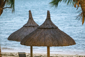 Sun umbrella and beach beds on tropical coastline, in Mauritius