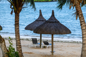 Sun umbrella and beach beds on tropical coastline, in Mauritius