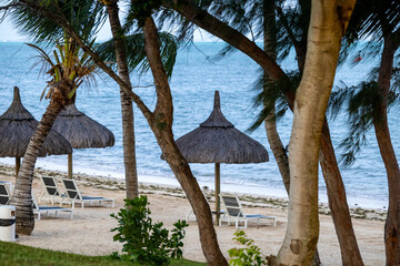 Sun umbrella and beach beds on tropical coastline, in Mauritius