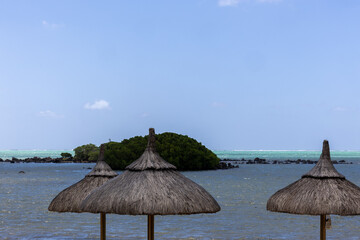 Sun umbrella and beach beds on tropical coastline, in Mauritius