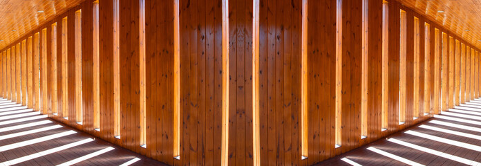 Lights and shadows in the hallway. Wall of planks with symmetrical distances where sunlight penetrates