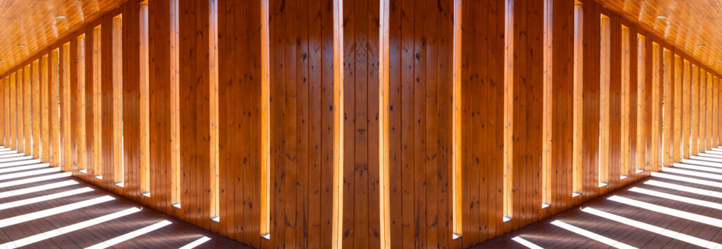 Lights and shadows in the hallway. Wall of planks with symmetrical distances where sunlight penetrates