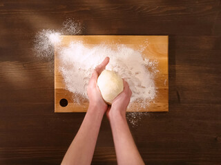 Rolling out the dough in flour on wooden board.