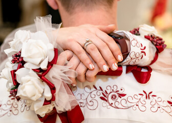 The bride's hand with a gold ring on the groom's shoulder
