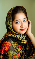 Studio portrait of  a Pakistani Woman in Traditional Headscarf, Shy, timid smile.  cultural diversity, traditional clothing, ethnicity, cultural heritage.