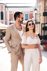 Beautiful fashion woman and her handsome elegant boyfriend. Sexy brunette model in summer clothes. Fashionable smiling couple posing in street Europe. Brutal man and female outdoors