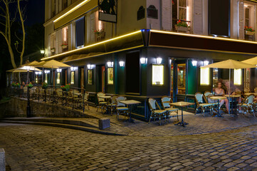 Typical night view of cozy street with tables of cafe and easels of street painters in quarter Montmartre in Paris, France. Cityscape of Paris. Architecture and landmarks of Paris - 764801446