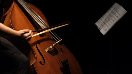 cellist playing cello under spotlight
